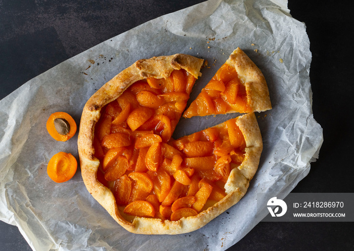 Delicious homemade French galette with ripe sweet apricots on a smooth dark background. Flat lay. Fr