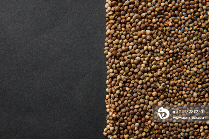 Many cannabis seeds covering half of the photo on a black background.