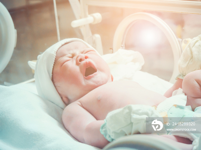 Newborn baby girl inside incubator in hospital post delivery room