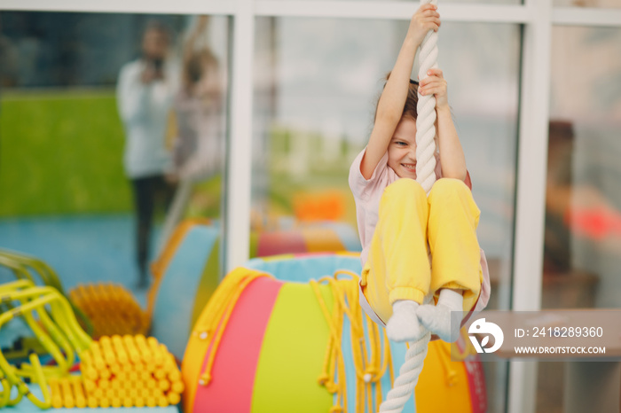 Kids doing exercises climbing tightrope in gym at kindergarten or elementary school. Children sport 