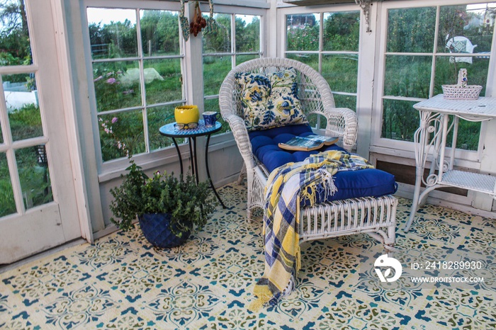 Beautifully decorated interior of a greenhouse/summer house with stenciled floor, white wicker chais