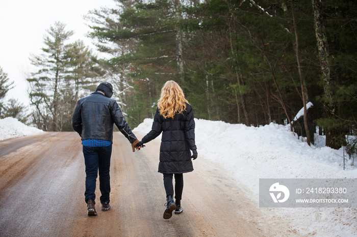 Rear view of couple walking on road in winter