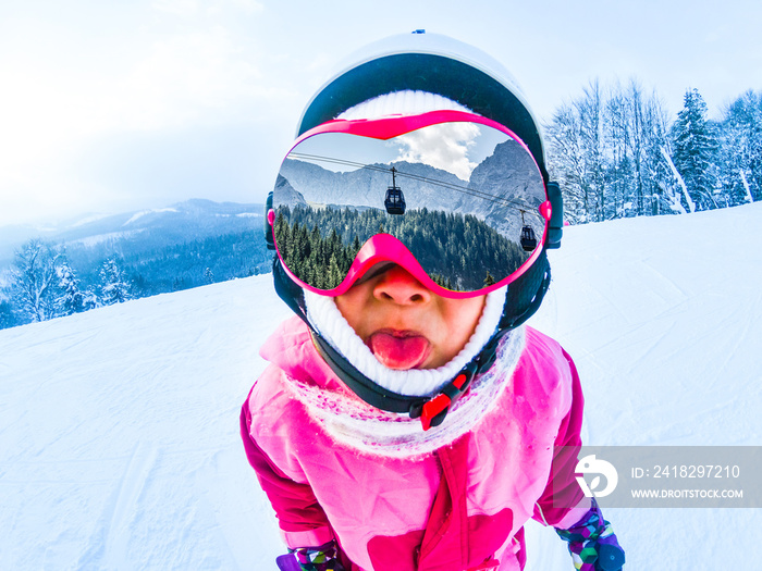 Little skier on snowy ski slope at sun winter day