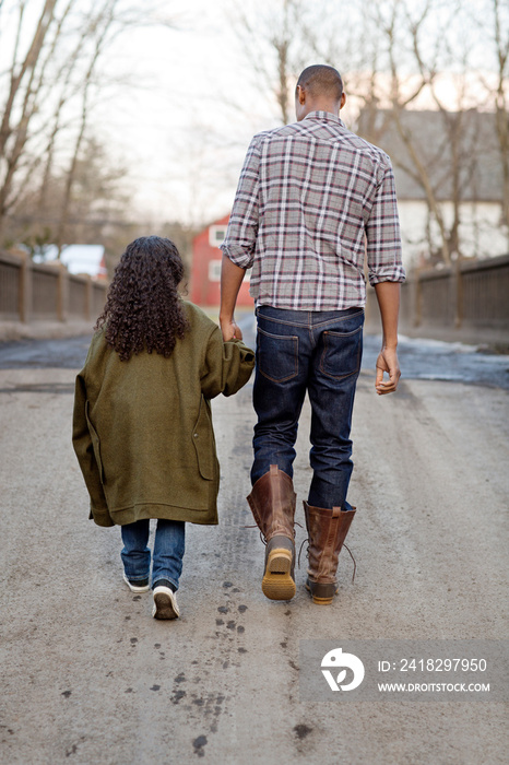 Father and daughter (6-7) walking holding hands