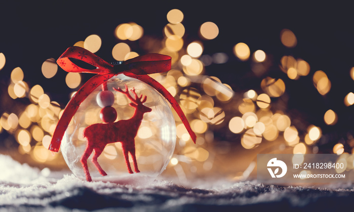 Christmas glass ball with a reindeer inside on snow.