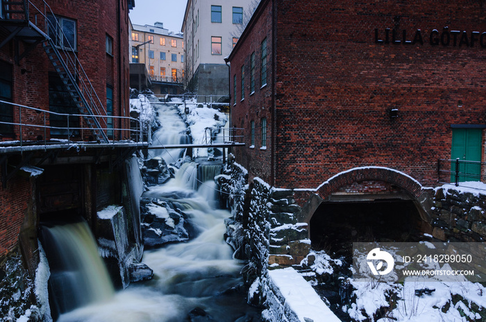 Old industrial buildings besides waterfall