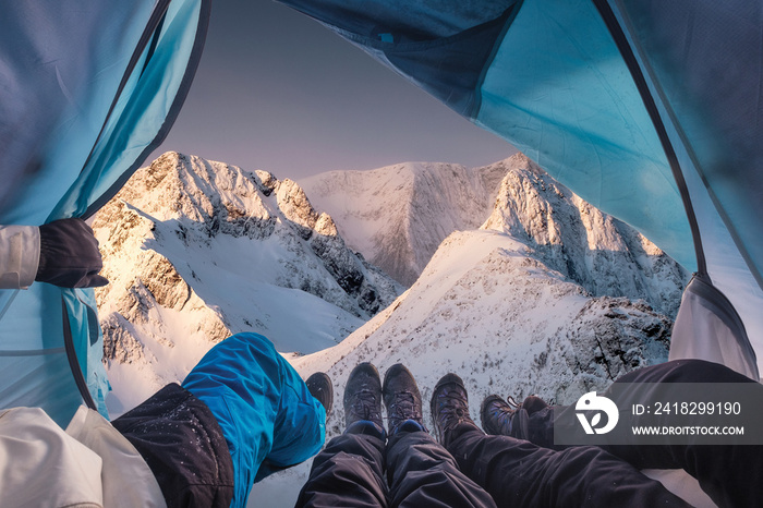 Group of climber are inside a tent with open for view of blizzard on mountain