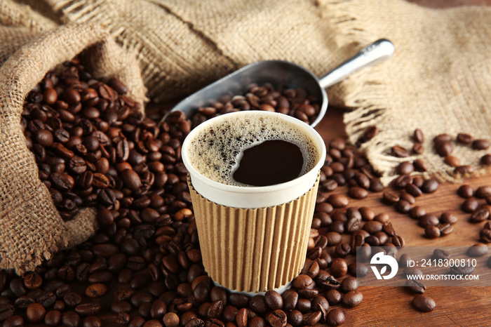 Cup of coffee with beans and scoop on table