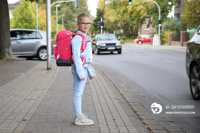 Mädchen mit Schultornister möchte die Strasse überqueren