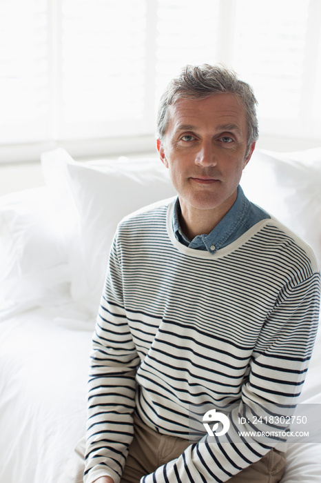 Portrait confident mature man sitting on bed