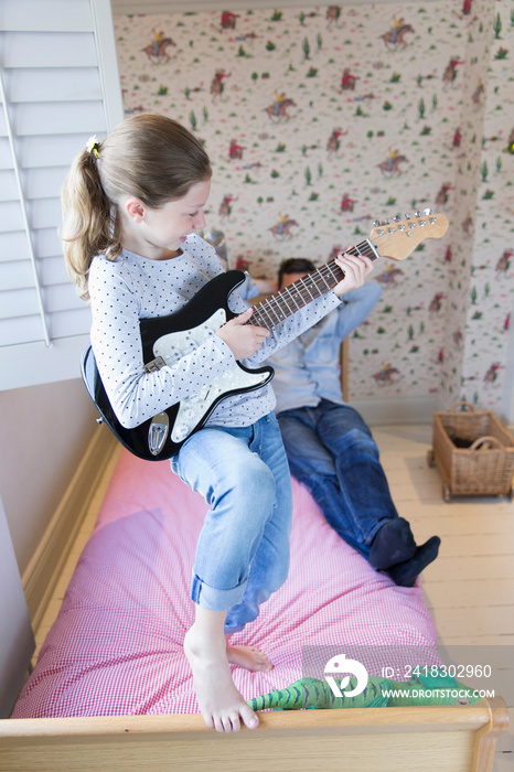 Girl playing guitar on bed