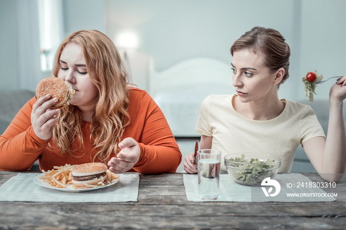 Enigmatical overweight female person smelling tasty burger