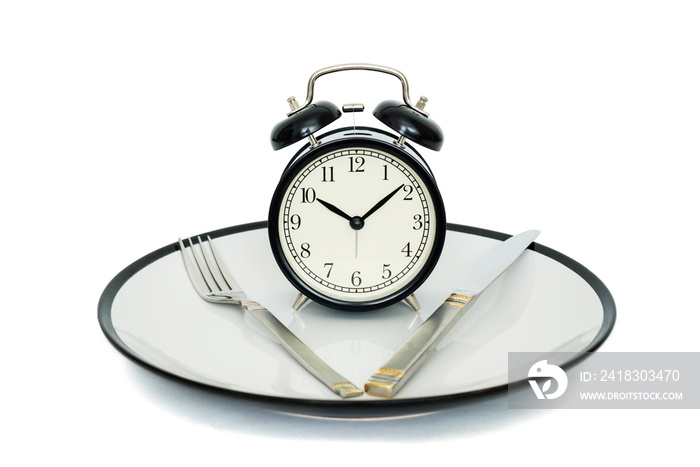 Black alarm clock with fork and knife on the plate. Isolated on white. Time to eat. Weight loss or d