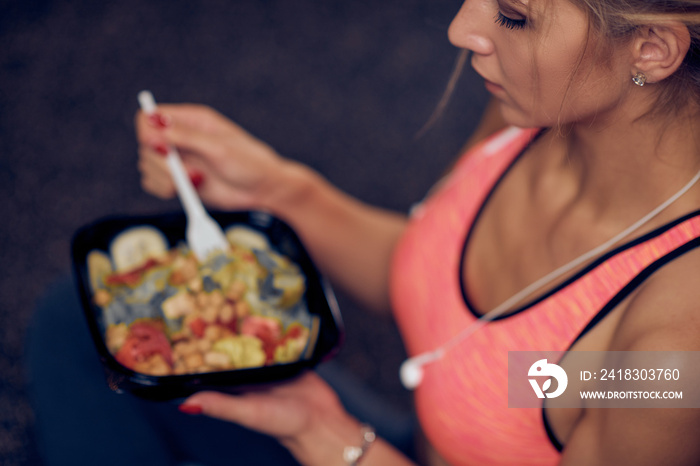 Top view of woman eating healthy food while sitting in a gym. Healthy lifestyle concept.