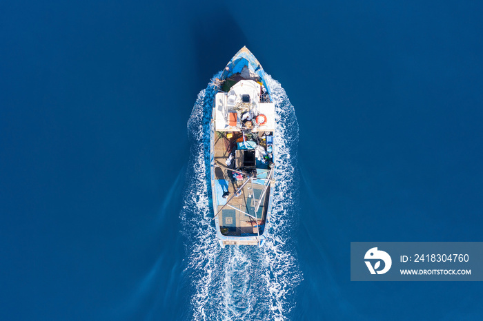 Small Fishing boat sailing across calm smooth Sea, Aerial view.