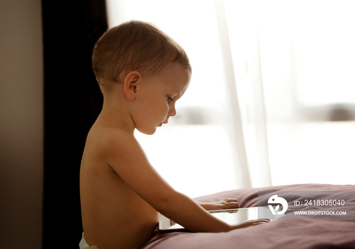 Baby boy (18-23 months) using tablet pc in bedroom