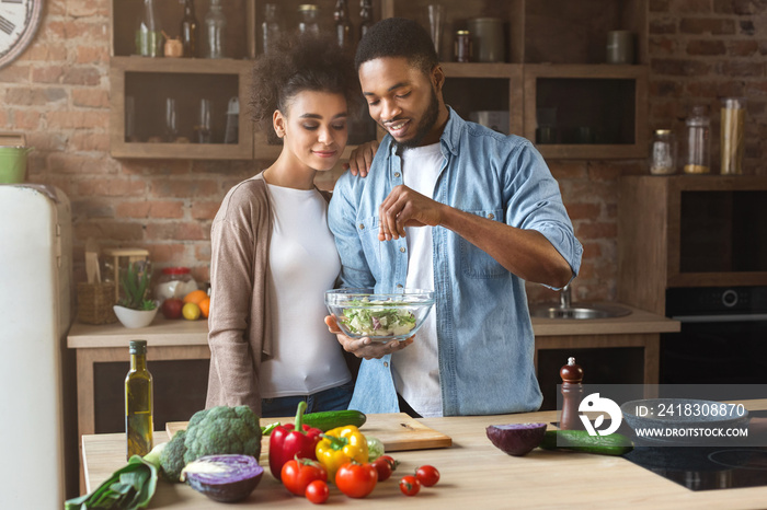 恩爱的黑人夫妇烹饪绿色健康沙拉
