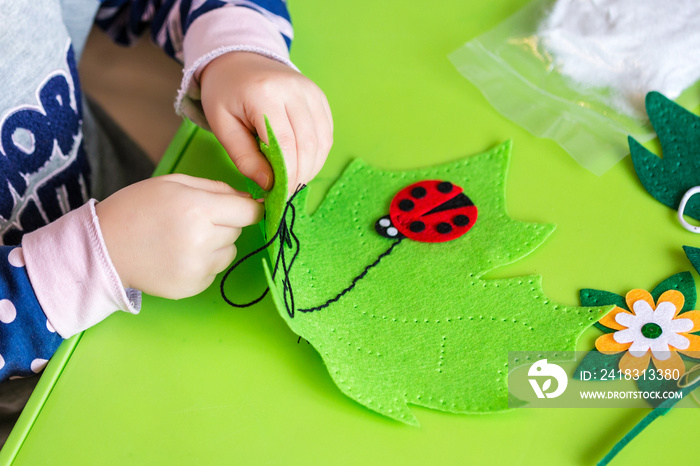 儿童制作绿叶和红色瓢虫的毛毡软玩具。儿童DIY活动。特写。孩子们哈