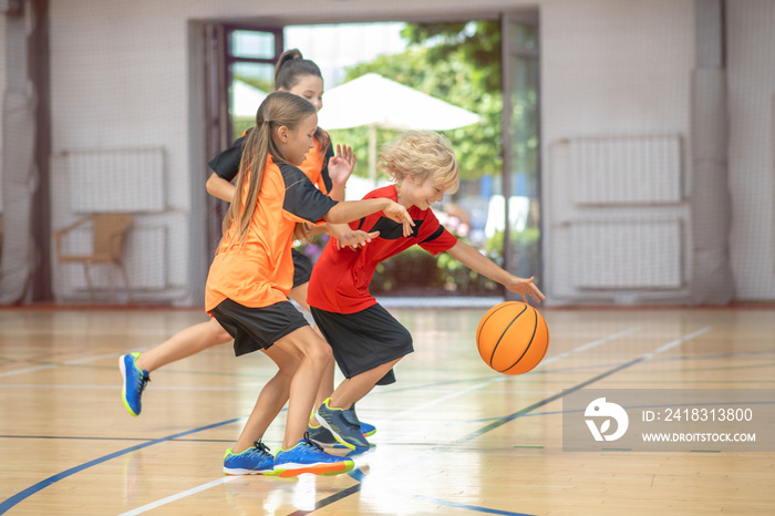 Kids in bright sportswear playing basketball together and feeling excited