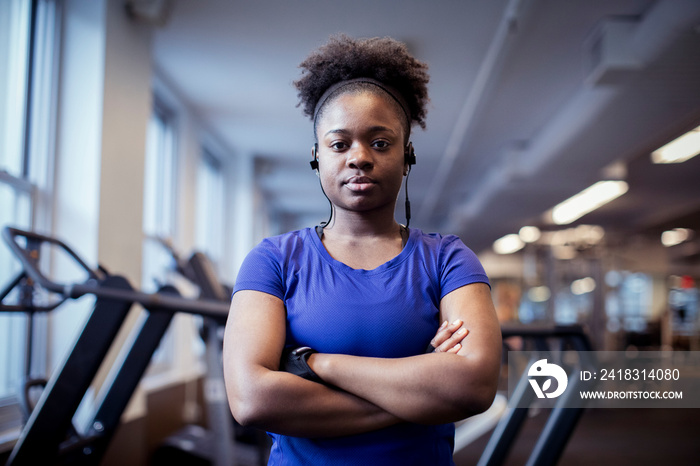 Portrait of serious female athlete with arms crossed standing in gym