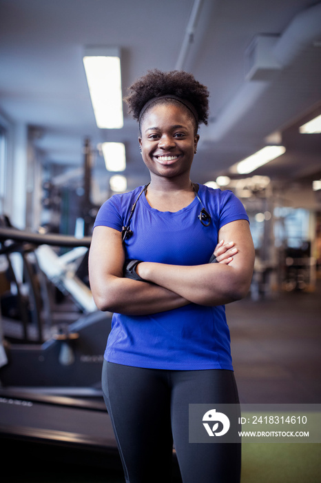 Portrait of smiling female athlete with arms crossed standing in gym