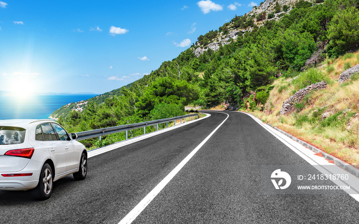 White car rushes along the road to the sea.