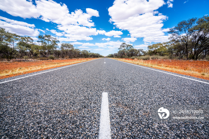 Straight road with white lines in middle of outback red centre Australia