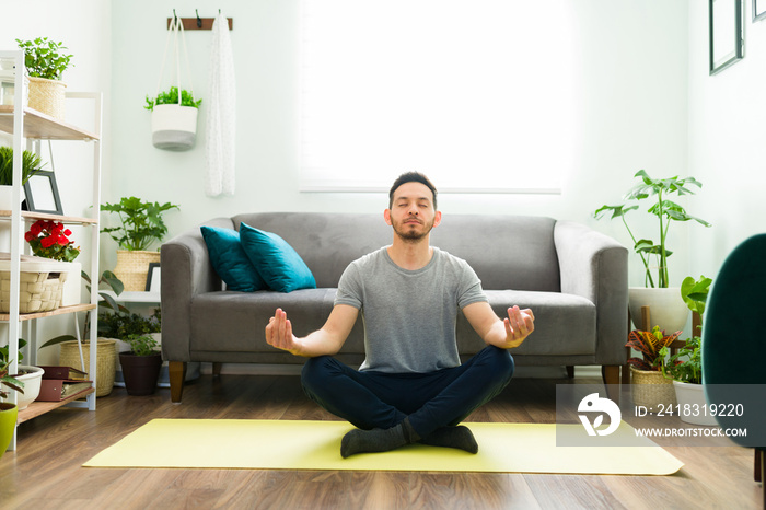 Hispanic man meditating at home and feeling relaxed