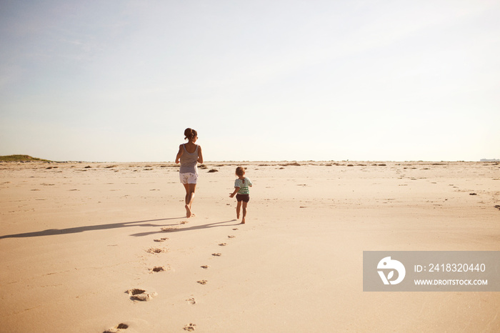 Mother and daughter (2-3) running on beach