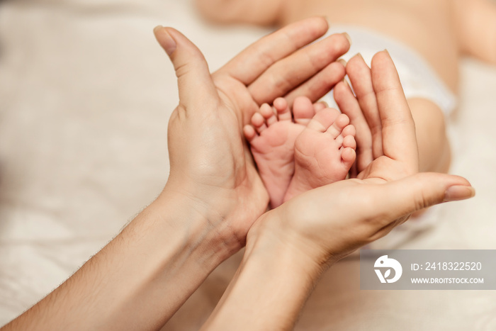 Mother holding tiny foot of newborn baby