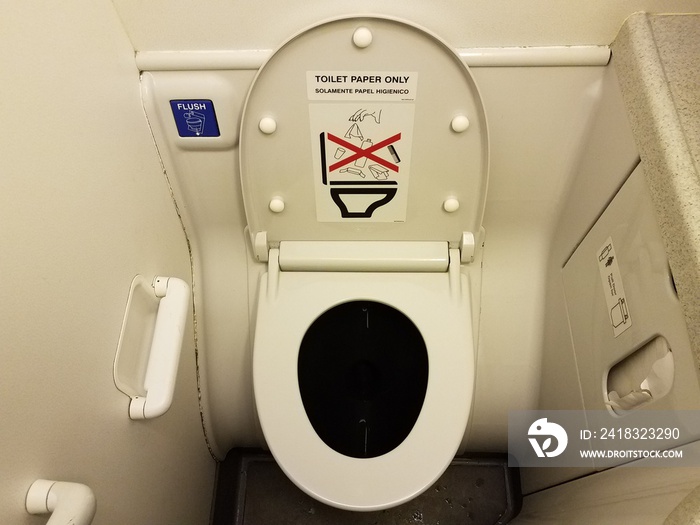 toilet paper only sign on airplane toilet lid and blue flush button