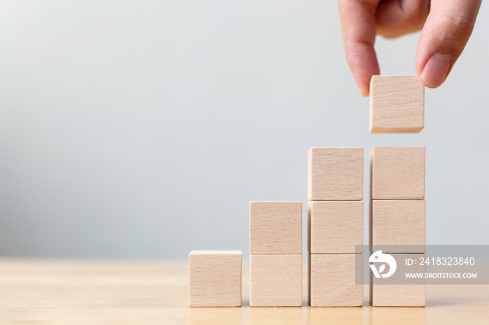 Hand arranging wood block stacking as step stair on wooden table. Business concept for growth succes