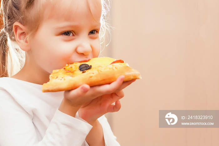 A young girl with plaits is eating a piece of pizza