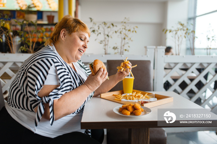 Fat woman eating high calorie food in restaurant