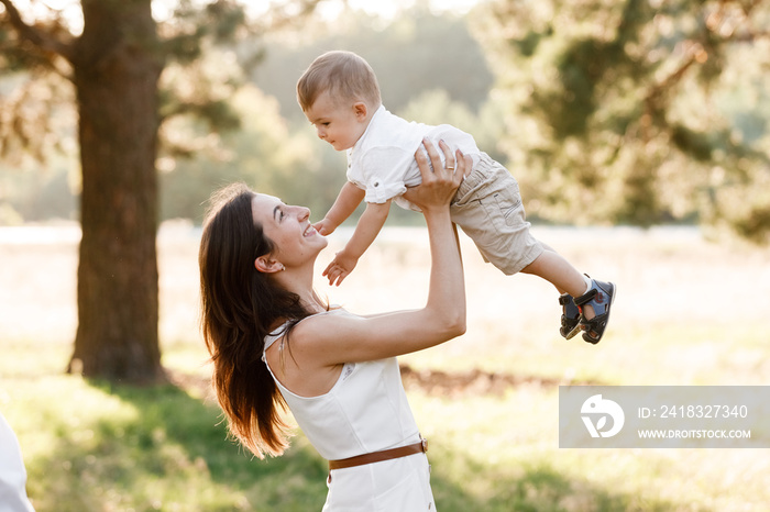 mom throws up and spins the son on nature on summer day vacation. mother and girl playing in the par