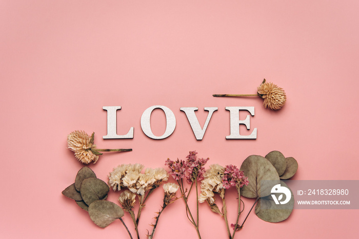 Creative flat lay of word love on soft color  background with natural plants