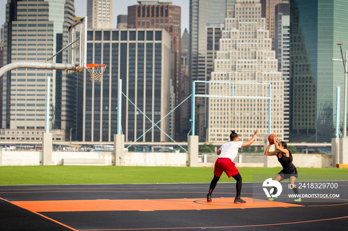 Young women playing basketball in court