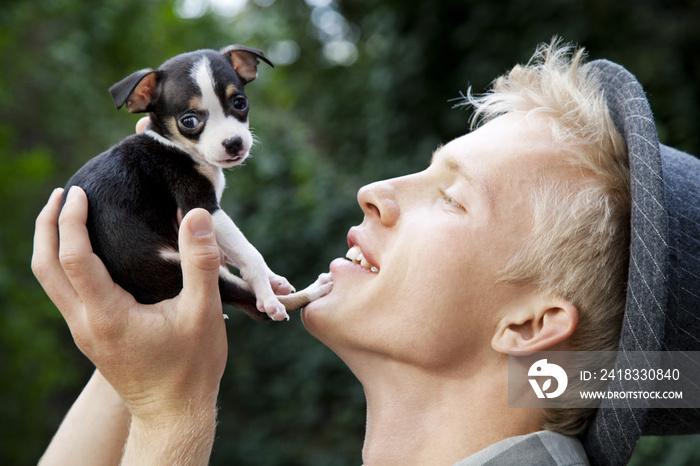 Close-up side view of man holding puppy at park