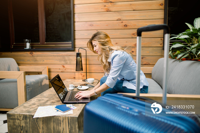 Business, travelling concept. Side view of pretty woman smiling, typing and looking on the laptop, w