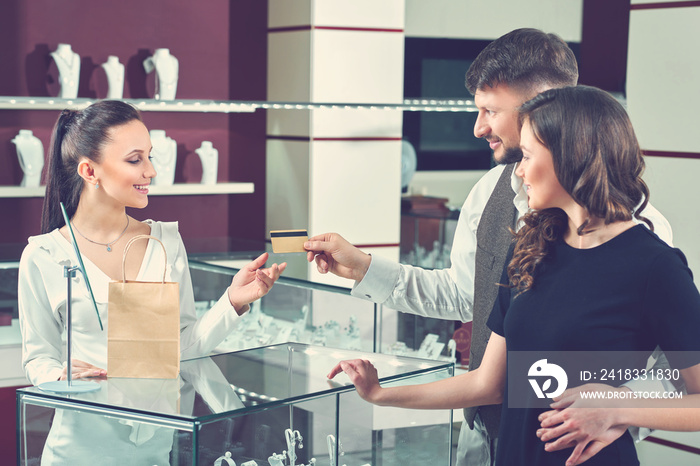 Happy couple in love paying with credit card at the jewelry stor