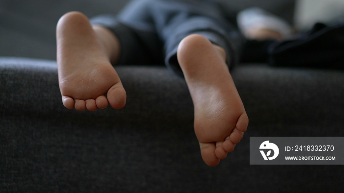 Child feet sleeping on couch small boy slouched on sofa