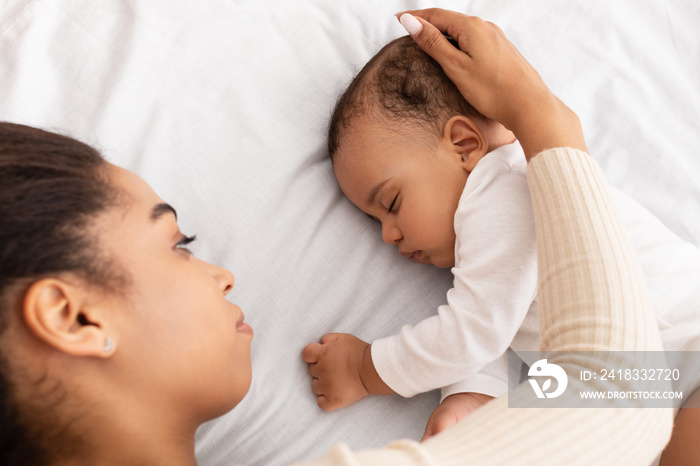 African Mom Stroking Sleeping Baby Lying In Bed Indoor