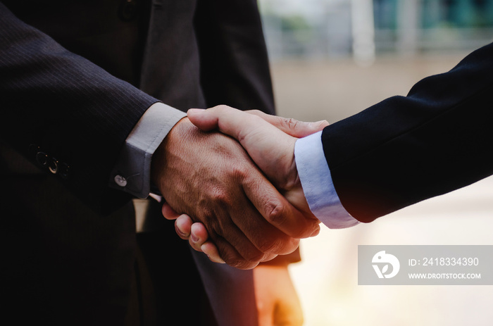 close up of business man in suit shaking hands after finishing up a business meeting in city with du