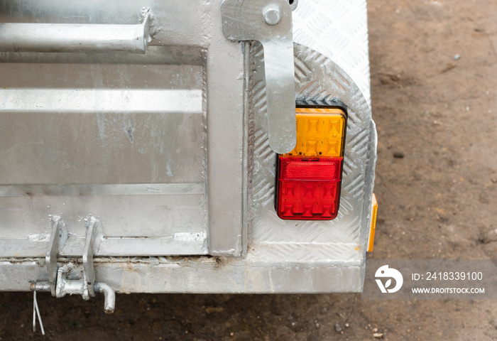 Close up cropped view of rear of car trailer door with brake and indicator lights (selective focus)