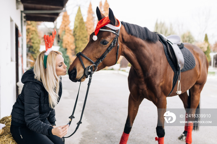 美丽的年轻女子在寒假里和她的马一起享受。
