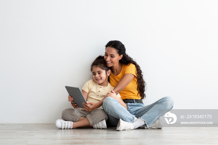 Family Leisure. Happy Arab Mother And Little Daughter Using Digital Tablet Together