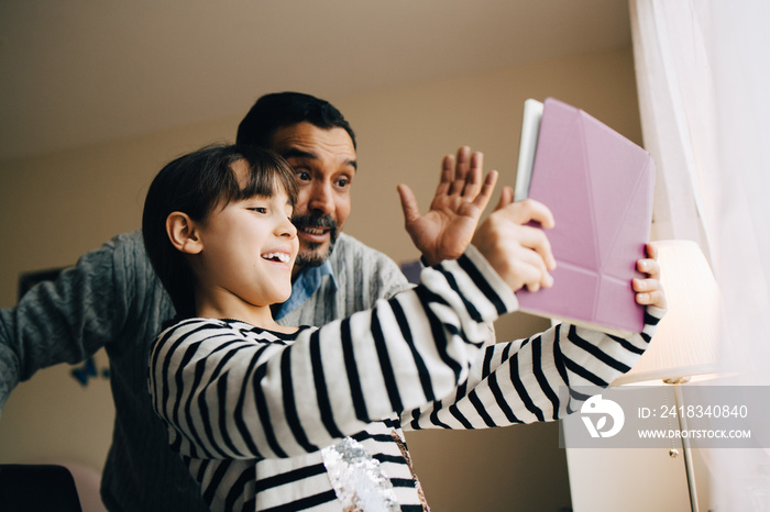 Smiling father and daughter doing video call on digital tablet at home