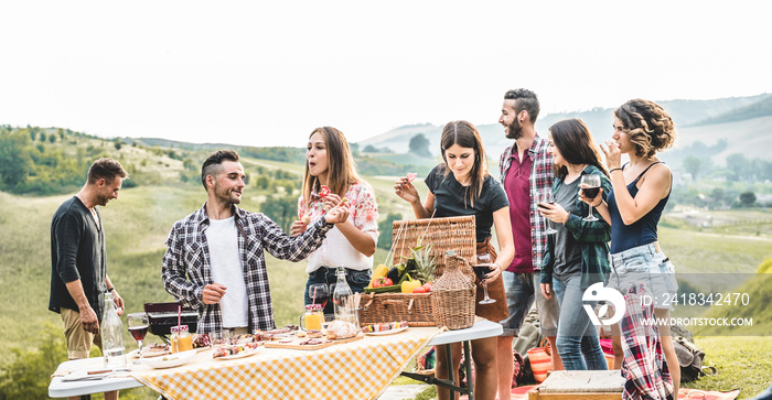 Happy adult friends eating at picnic lunch in italian vineyard outdoor - Young people having fun on 