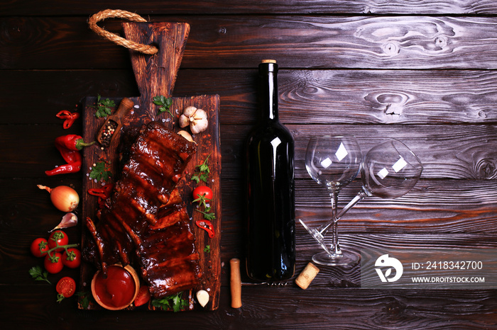 Grilled pork ribs with bottle of red wine spices and vegetables on wooden background