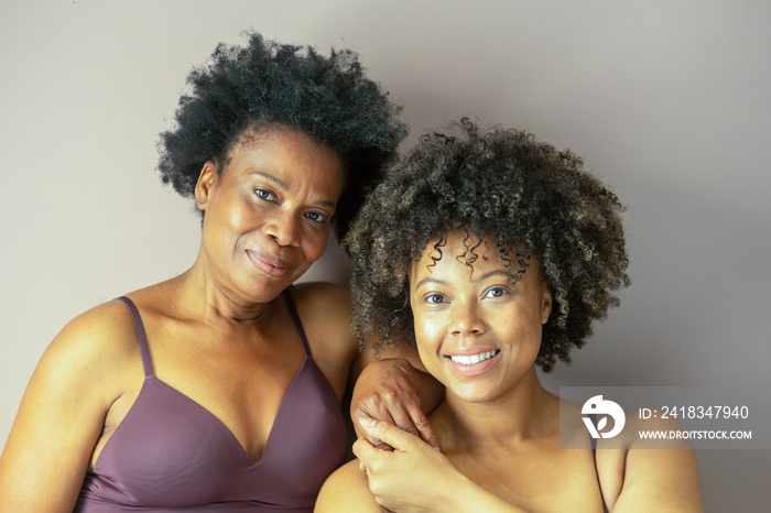 Studio portrait of smiling mother and daughter wearing lingerie